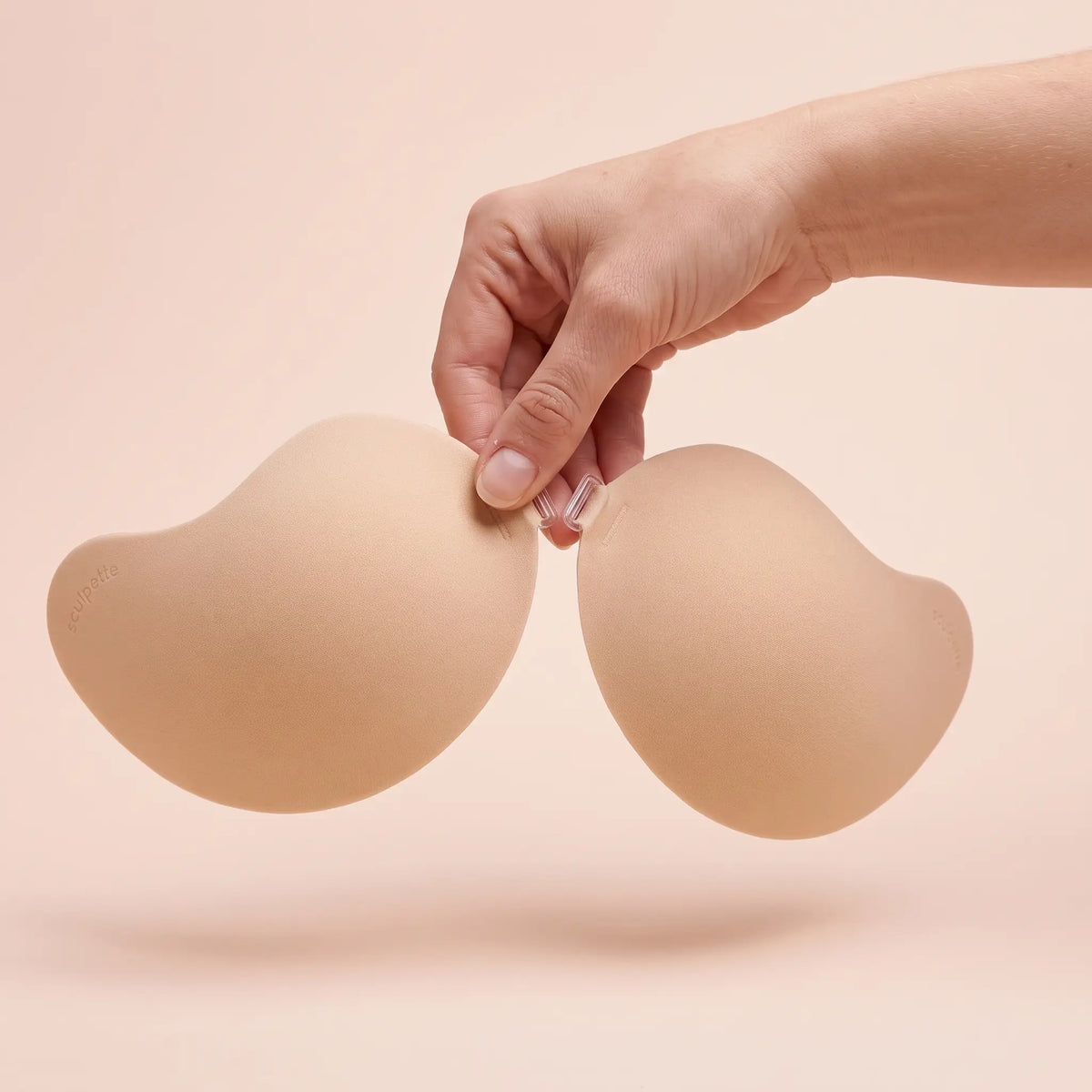 The Invisible Bra held up by its clasp to show the size of the cups