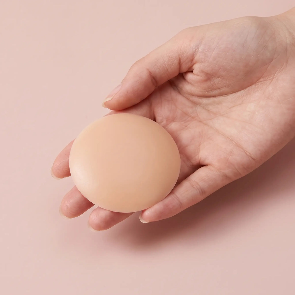 A round nude cover held on the fingertips to show its diameter