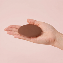 The Sculpt Round cover in Cocoa on an open hand to show its true size