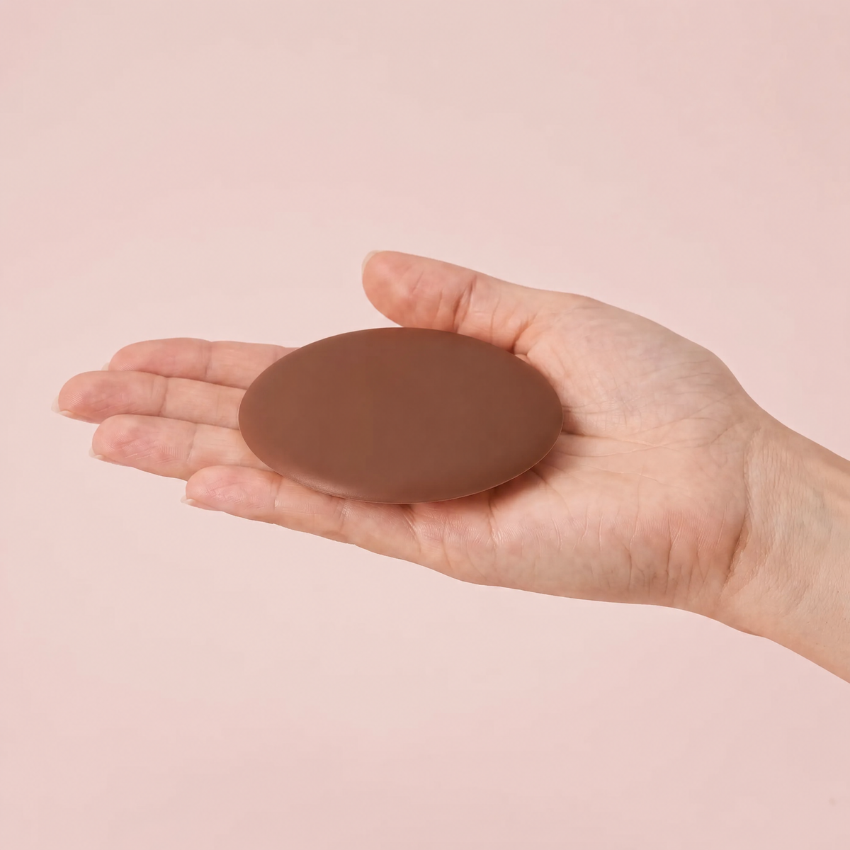 The Sculpt Round cover in Cocoa on an open hand to show its true size