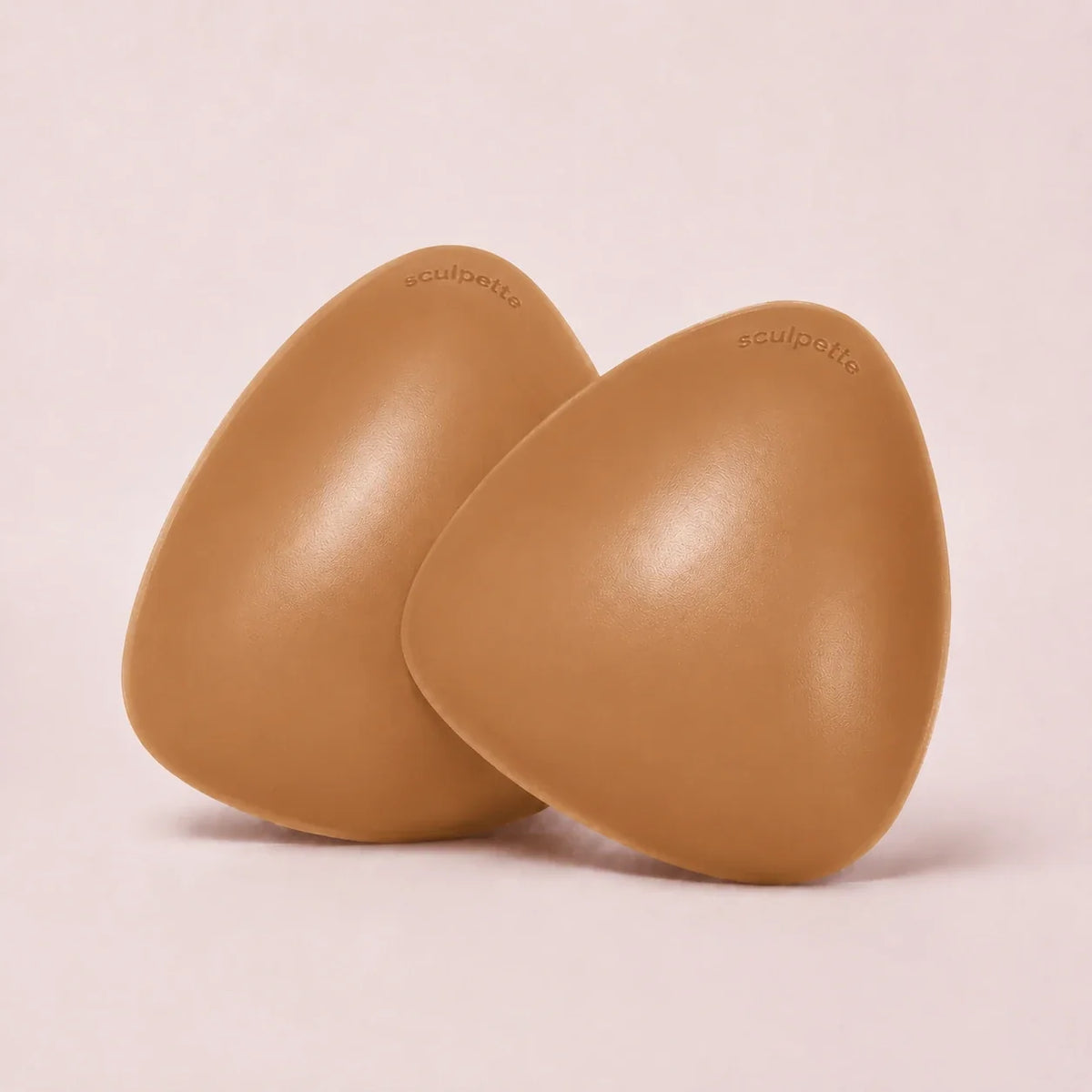 A pair of The Sculpt adhesive bra inserts in Caramel standing side by side