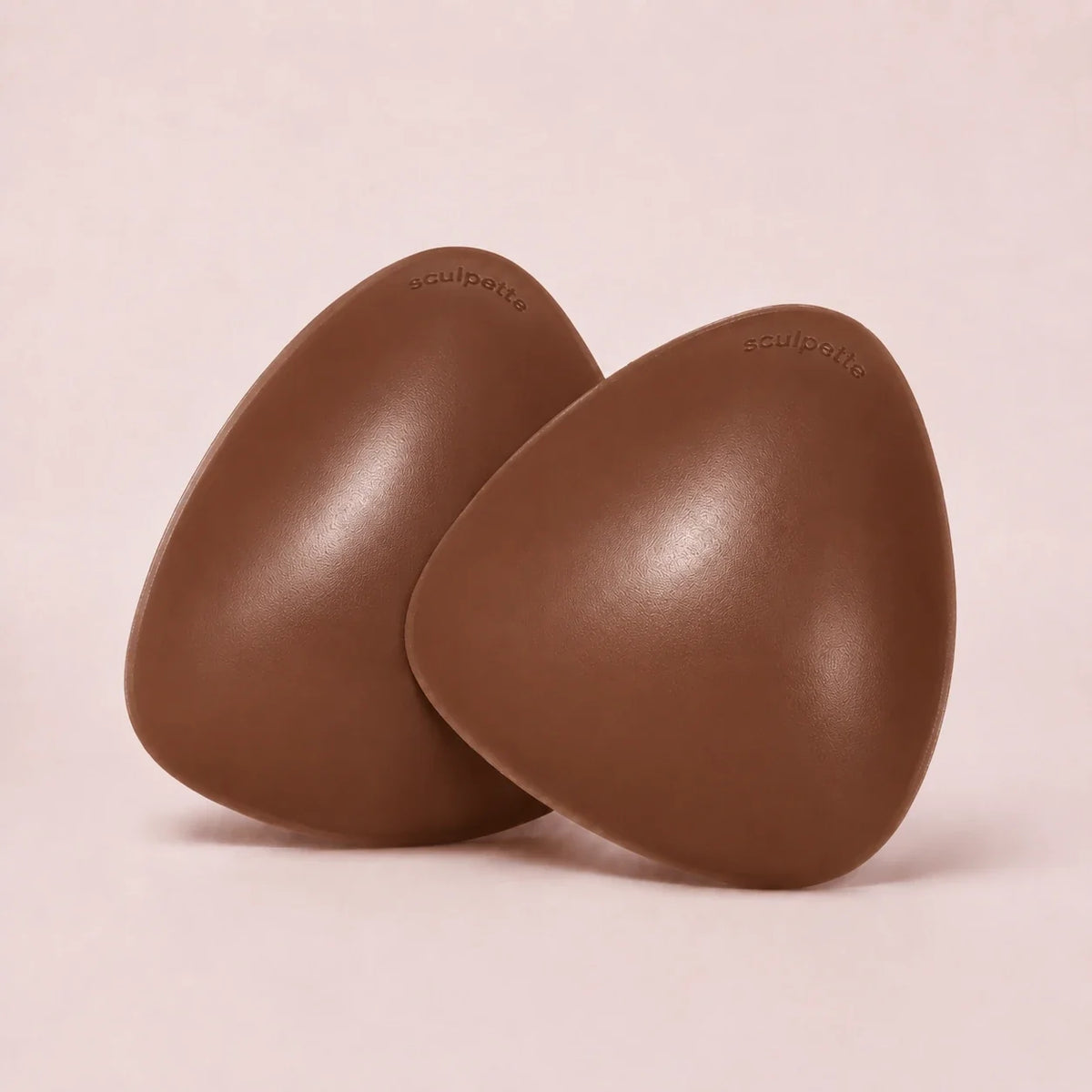 A pair of The Sculpt adhesive bra inserts in Cocoa standing side by side